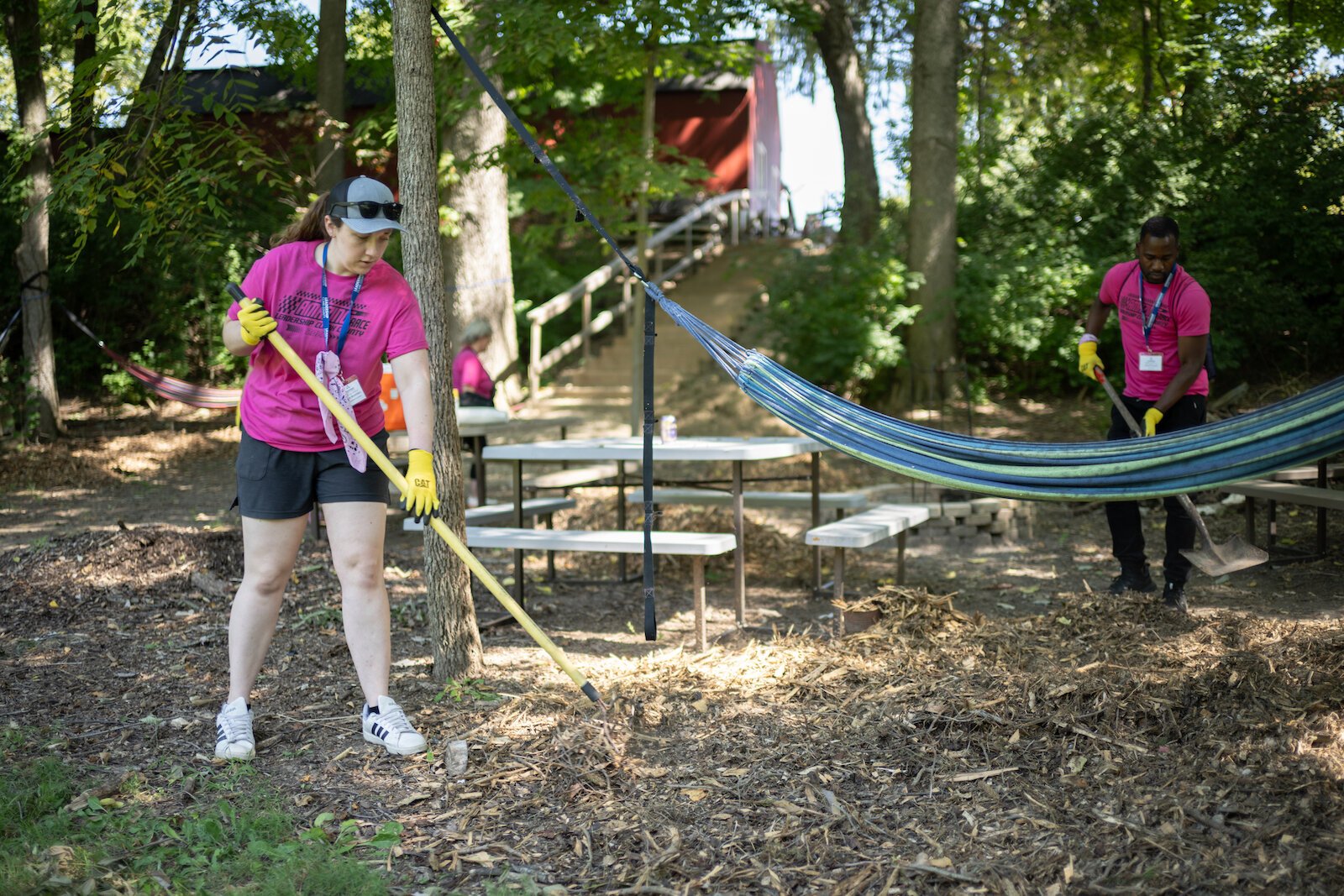 Amazing Race participants spread mulch in a picnic area.