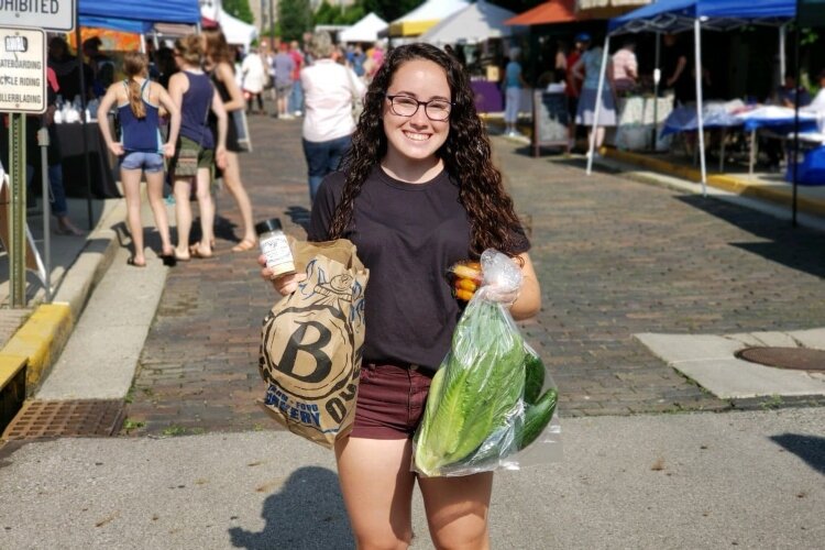 A shopper at a former Springfield Farmers Market shows off her purchases. The market will open June 13 but will be more spaced out than in past years.