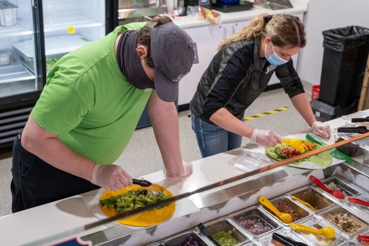 Fresh Abilities employee David King and restaurant manager Marlee Lloyd work on building wraps.