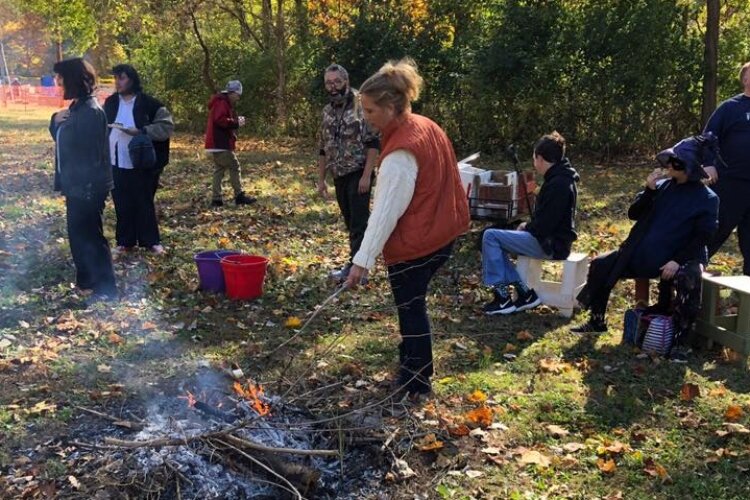 Jennifer Hardacre, owner of The H.A.R.D. Acre Farm, roasts a marshmallow over a campfire during a fall celebration on the farm. "Farmers" who visit are all adults with developmental disabilities who the farm helps to teach during visits.