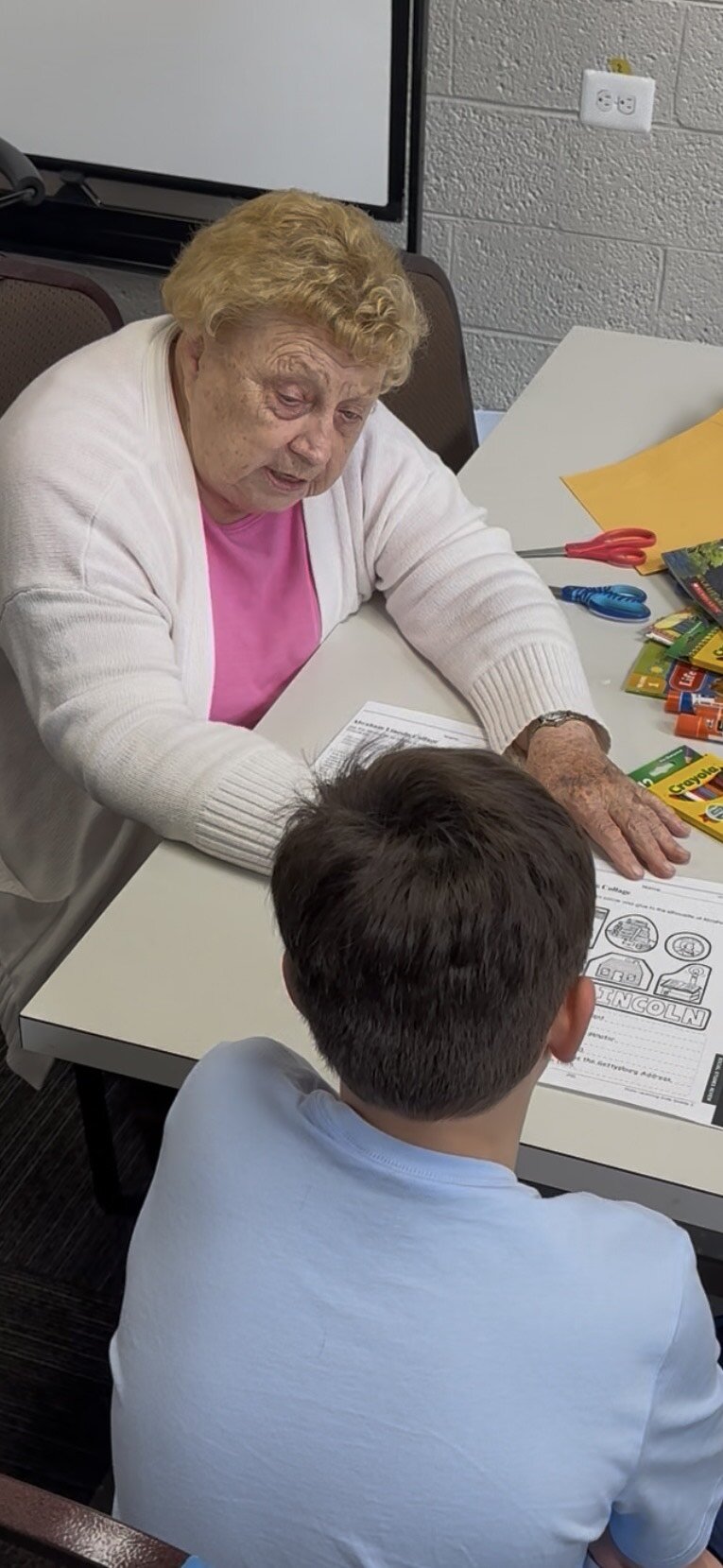 A volunteer works with a young student who is working to reach a higher reading level.