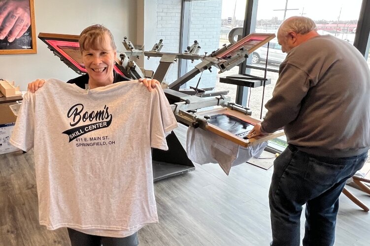 Roy Boomshire makes a screenprinted T-shirt and his wife, Carla, holds up one he just completed.