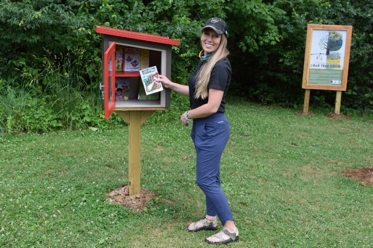 Ohio Department of Natural Resources Alyssa Yaple shows off some of the collection of books in the Little Free Library at the entrance of the Storybook Trail at John Bryan State Park in Yellow Springs.